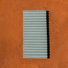 an orange wall with a small window in it