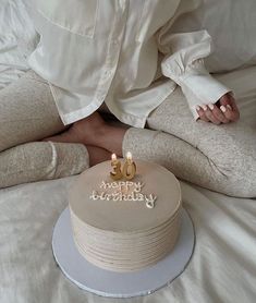 a person sitting on a bed with a birthday cake