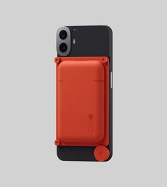 an orange iphone case with a camera attached to the back of it, on a gray background