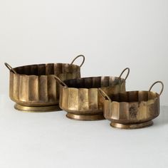 four antique brass pots sitting on top of each other