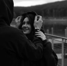 a man and woman standing next to each other in front of a body of water