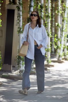 a woman in white shirt and jeans walking down the street