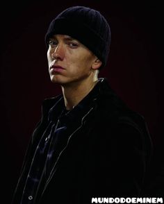 a young man wearing a beanie and looking off to the side in front of a dark background