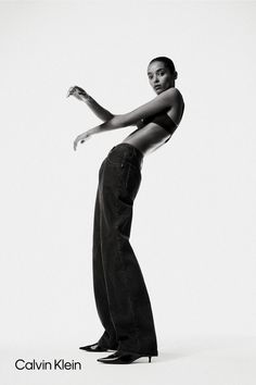 a black and white photo of a woman in high rise jeans with her arms outstretched