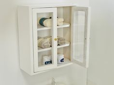 a bathroom cabinet that has towels and other items in it