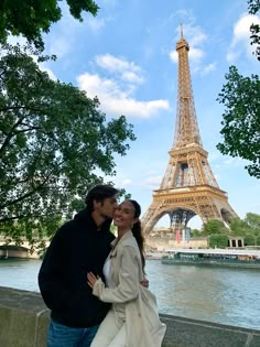 a man and woman standing next to each other near the eiffel tower in paris