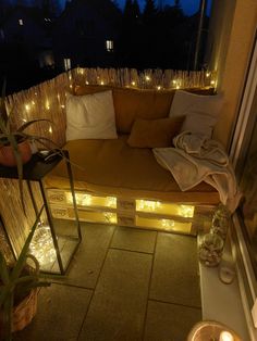 a couch sitting on top of a patio next to a window covered in string lights