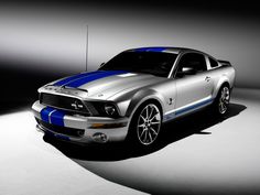 a silver and blue mustang car in a spotlight