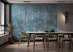 a dining room with a table and chairs in front of a blue wall that has white flowers on it