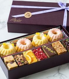 a box filled with lots of different types of food next to a purple ribbon on top of a table