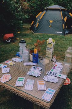 an outdoor picnic table with cards and bottles on it