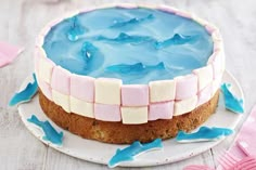 a cake with blue icing and marshmallows is on a white plate