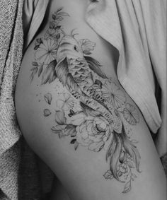 a black and white photo of a woman's thigh with a koi fish tattoo