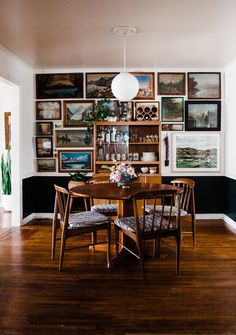 a dining room table with chairs and pictures on the wall