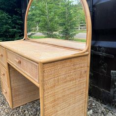 a wicker desk with a mirror on it in front of a black truck and trees