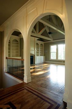 an empty living room with wood floors and arches