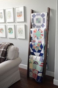 a living room filled with furniture and pictures hanging on the wall behind a wooden ladder