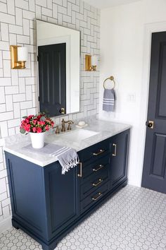 a white and blue bathroom with two sinks on the same vanity, gold faucet