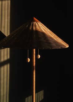 a bamboo umbrella with two balls hanging from it's side in the dark room