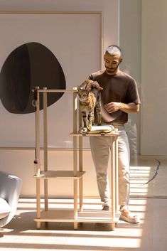 a man standing next to a cat on top of a wooden stand in front of a painting