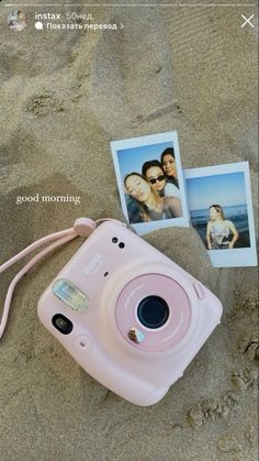 a pink camera sitting on top of a sandy beach next to two polaroid pictures