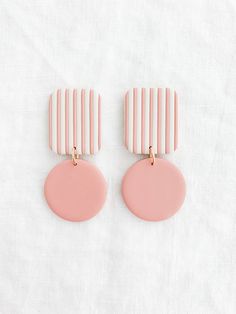 two pink and gold earrings sitting on top of a white sheet