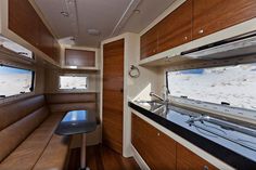 the inside of a camper with wood paneling and leather seats, windows, and counter space