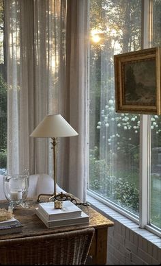 a table with a lamp on top of it next to a window covered in curtains