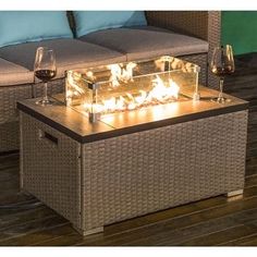 a fire pit sitting on top of a wooden floor next to two glasses of wine