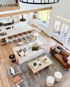 an aerial view of a living room and kitchen area with hardwood floors, white walls, large windows, and lots of furniture