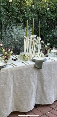 the table is set with white flowers and candles for an outdoor dinner party or celebration