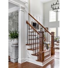 the stairs in this house are made of wood and wrought iron railings, along with potted plants