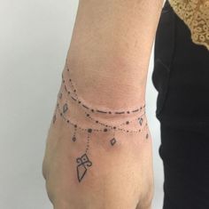 a woman's hand with a tattoo on it and a chain around the wrist