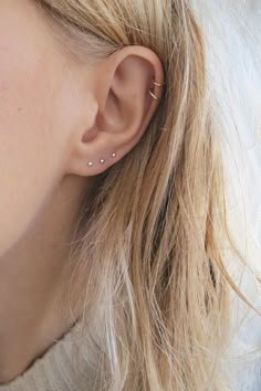 a close up of a person's ear with two small piercings on it