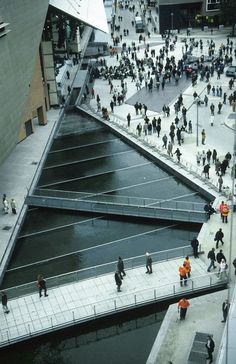 an aerial view of people walking on the sidewalk near a body of water in a city