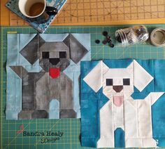 two dogs made out of fabric sitting on top of a cutting board next to a cup of coffee