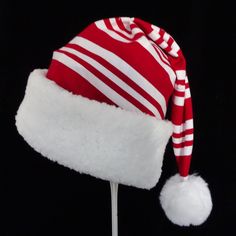 "This novelty Santa hat is made up in a Christmas red and white candy cane striped soft cotton flannel fabric. The hat brim is a snowy white faux Sherpa fur fabric. The sizing on the hat is generous and will fit most adult or teen head sizes. The styling is the classic slouch stocking cone, traditional Santa look. There is a snowy white pompom stitched on the top. Opening measurement is 24-25\" circumference, tapering in cone style and the length of the hat is 19\". Please check the measurements Candy Cane Santa Hat, White Christmas Cap, White Christmas Holiday Hat, Red Santa Hat, Red Christmas Cap, Adjustable Striped Winter Hat, Cheap Red Holiday Hats, Red Adjustable Holiday Hat, Candy Cane Accessories