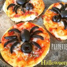 three small pizzas with black toppings are on a tray and have spider decorations