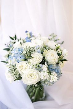 a bouquet of white and blue flowers in a vase