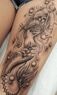 a woman's thigh with a mermaid tattoo on it