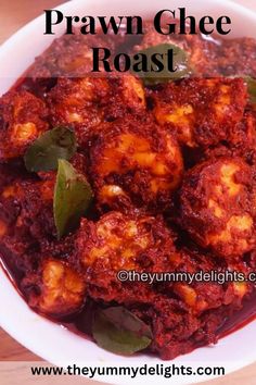 a white bowl filled with food on top of a wooden table and text overlay reads praw ghee roast