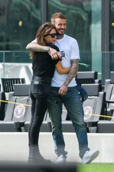 a man and woman hugging each other in front of a stadium