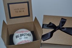 a baseball in a box with a black ribbon around it and a card that says, you're going to be a big brother est 200