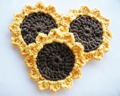 three crocheted sunflowers sitting on top of a white countertop next to each other