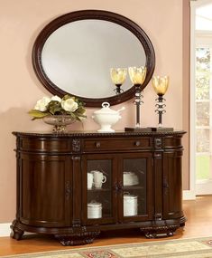 a large round mirror on top of a wooden cabinet with two vases in front of it