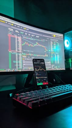 a cell phone sitting on top of a desk next to a computer monitor and keyboard