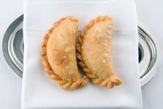 two pastries sitting on top of a white napkin next to a silver dish drainer