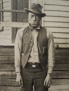 an old black and white photo of a man wearing a hat, vest and tie