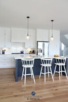 a kitchen with white cabinets and blue island in the center is surrounded by wooden flooring