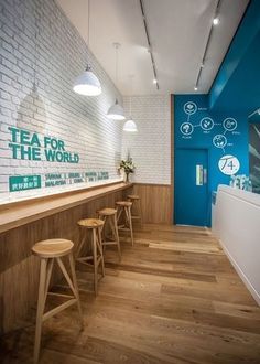 the interior of a tea shop with wooden stools and white brick wall behind it